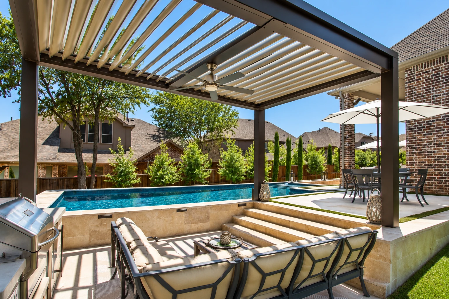 Outdoor patio with an adjustable louvered pergola, lounge seating, dining area, and swimming pool.